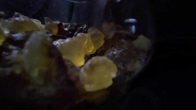 Macro video of Frankincense resin over a black background. Sharp focus on textures and amber colors, perfect for organic and wellness visuals.