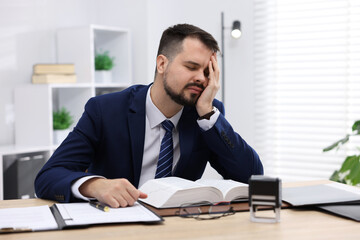 Naklejka premium Man feeling fatigue at wooden desk in office