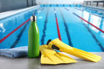 Swimming lesson. Yellow flippers, bottle and towel by swimming pool © New Africa