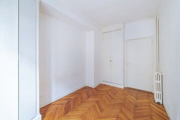 Empty bright room with herringbone wooden floor in renovated apartment