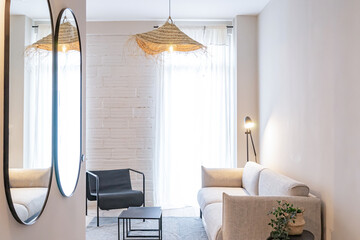 Cozy modern living room with round mirror and soft natural light.