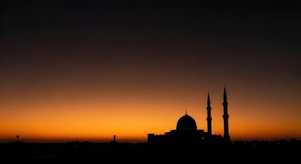 Obraz premium A beautiful silhouette of a mosque against a vibrant sunset. The sky transitions from a deep, dark blue at the top to a brilliant orange glow along the horizon.