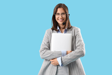 Fototapeta premium Female technical support agent in headset with laptop on blue background