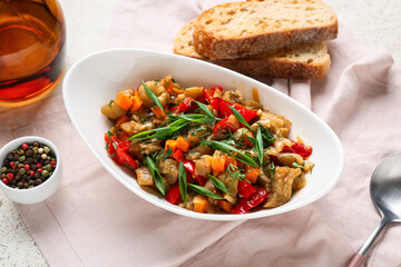 Bowl of vegetable stew served with bread slices and green onion on light background