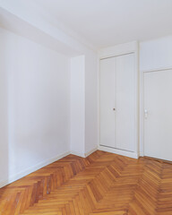 Empty bright room with herringbone wooden floor in renovated apartment.