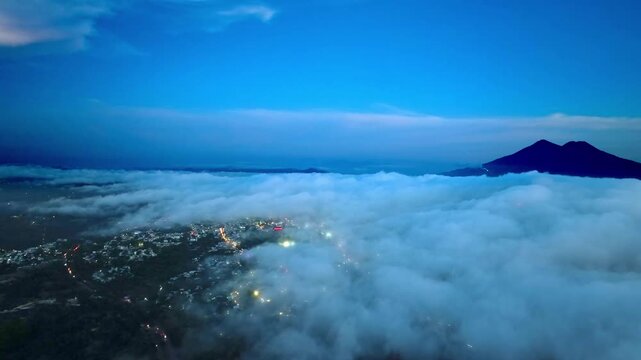 Video con dron, volando de noche sobre la ciudad con muchas nubes y luces de la ciudad 