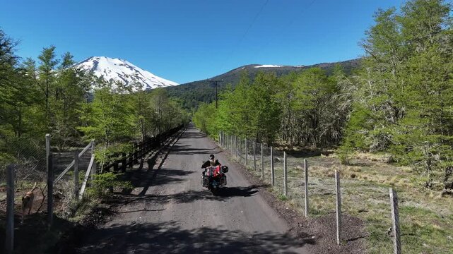 Motorcyclist and adventure bike standing before Lonquimay Volcano. Malalcahuello National Reserve, Chile.