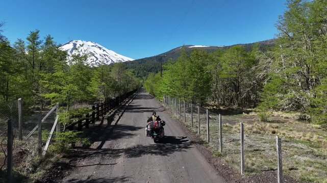 Motorcyclist and adventure bike standing before Lonquimay Volcano. Malalcahuello National Reserve, Chile.