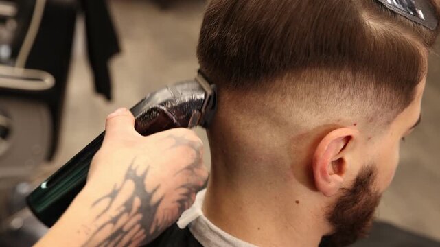 Stylist cutting man's hair with clipper in barbershop, closeup