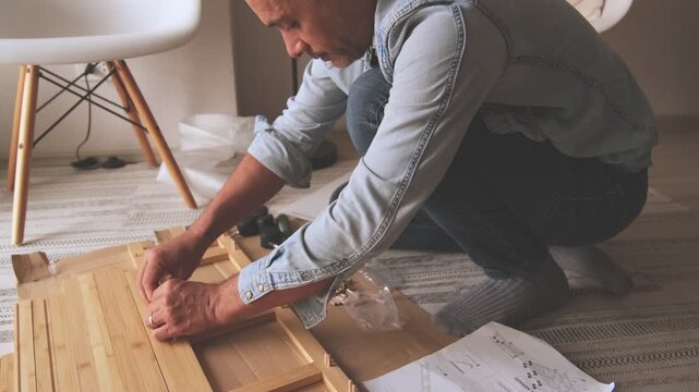Unrecognizable person assembling flat-pack furniture at home following the instructions