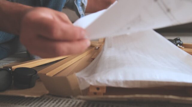 Close-up of a man's hands opening a cardboard box and reading the instruction manual to assemble furniture