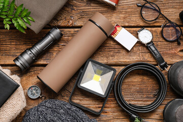 Composition with modern thermos, travel items and clothes on wooden background