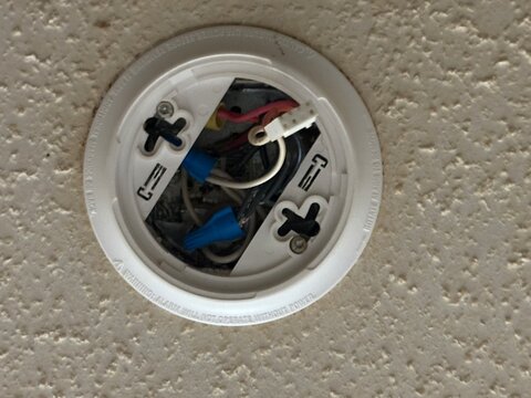 Exposed ceiling wiring inside recessed light fixture on textured popcorn ceiling