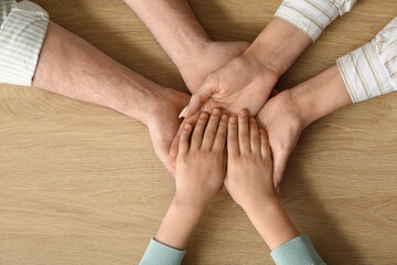 Couple with adopted girl holding hands on table, top view