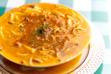 ひき肉の旨味が溶け出したソースにパスタを合わせた, ボロネーゼのスープパスタ。熱々のスープと麺が絡み合う様子や, 冬の温かメニュー, イタリアンレストランの新作を伝える販促・広告用素材に。 | a bolognese soup pasta with savory ground meat sauce and noodles in a warm broth.