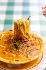 ひき肉の旨味が溶け出したスープにパスタを絡め、ボロネーゼのスープパスタをフォークで高く持ち上げるリフトアップ。麺に絡むソースの質感や、イタリアンレストランのランチ・ディナーメニューを伝える販促・広告用素材に。 | Lifting Bolognese soup pasta with a fork to show the savory meat sauce and noodles.