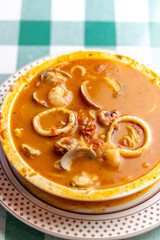 イカ、タコ、アサリ、ホタテを贅沢に使い、魚介の出汁が溶け出したシーフードのトマトソーススープパスタ。色鮮やかなトマトスープと豊富な具材が絡み合う、イタリアンレストランの看板メニューや冬の温製パスタを伝える販促・広告用素材に。 | A seafood tomato sauce soup pasta with squid, octopus, clams, and scallops in a rich 