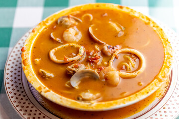 イカ、タコ、アサリ、ホタテを贅沢に使い、魚介の出汁が溶け出したシーフードのトマトソーススープパスタ。色鮮やかなトマトスープと豊富な具材が絡み合う、イタリアンレストランの看板メニューや冬の温製パスタを伝える販促・広告用素材に。 | A seafood tomato sauce soup pasta with squid, octopus, clams, and scallops in a rich 