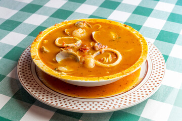 イカ、タコ、アサリ、ホタテを贅沢に使い、魚介の出汁が溶け出したシーフードのトマトソーススープパスタ。色鮮やかなトマトスープと豊富な具材が絡み合う、イタリアンレストランの看板メニューや冬の温製パスタを伝える販促・広告用素材に。 | A seafood tomato sauce soup pasta with squid, octopus, clams, and scallops in a rich 