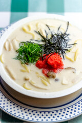 明太子、大葉、刻み海苔を添え、クリーミーな和風ホワイトソースにパスタを合わせた一皿。明太子のつぶつぶ感と薬味のアクセント、和洋折衷の優しい味わいを伝えるランチやディナーメニューの販促・広告用素材に。 | A Mentaiko (cod roe) and white sauce pasta topped with Shiso leaves and shredded Nori seaweed.