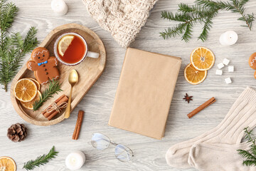 Composition with blank book, cup of tea, spices and burning candles on light wooden background