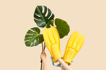 Female hands with flippers and monstera leaves on beige background. Travel concept © Pixel-Shot