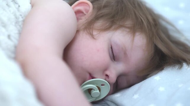 Close-up of peaceful newborn baby boy sleeping with pacifier on blue bedding