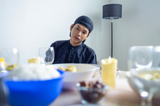 Hungry Asian Man Looking At Food On Table While Waiting For Bedug Maghrib During Ramadan Fasting