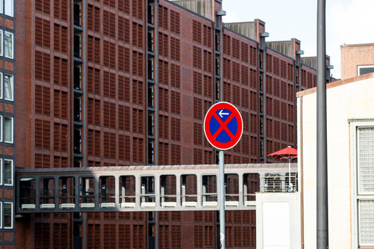 Urban street scene with blue red No Parking sign showing traffic restriction near modern building architecture and city control rules