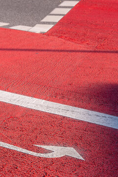 Road arrow direction painted in red and white lines on asphalt creating abstract traffic marking for navigation and safety background