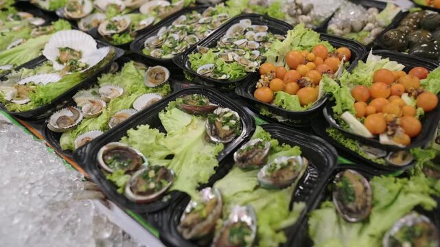 Fresh Seafood Platters On Ice, Rows Of Black Trays Filled With Lettuce, Abalone Shells And Oysters, Small Orange Tomatoes As Garnish, Crushed Ice Bed Keeping Seafood Chilled, Closeup Texture