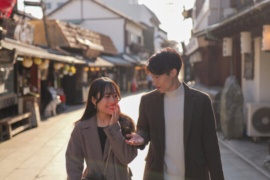 柴又の観光地を笑顔で話しながら歩くカップル