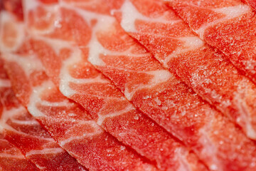 The delicate marbled texture of bright red frozen pork slices