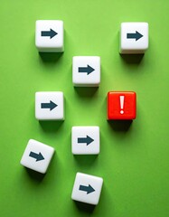 White cubes with arrows point mostly right, one red cube with exclamation