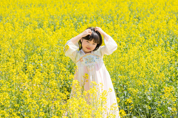 Fototapeta premium A girl in Hanfu in a spring rapeseed flower field