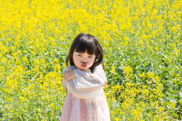 Fototapeta premium A girl in Hanfu in a spring rapeseed flower field