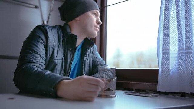 Leisurely Train Journey: Man Enjoying Tea, Video Calling, and Taking in Scenic Views