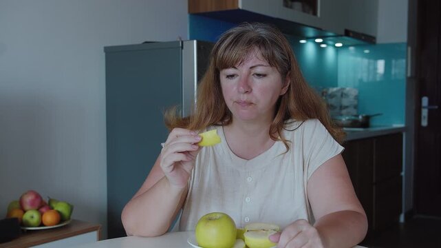 Close-up of a woman eating a green apple against the background of a kitchen