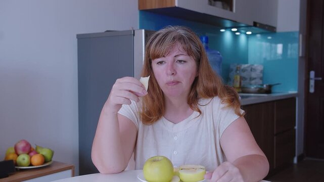 A woman eats a green apple in the background of a kitchen, close-up