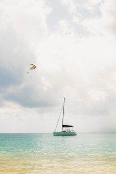 Parasailer soars above turquoise tropical waters, catamaran anchored below.