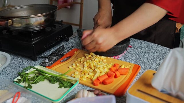 Close-up of hands grind sweet corn kernels in traditional stone mortar for corn fritters