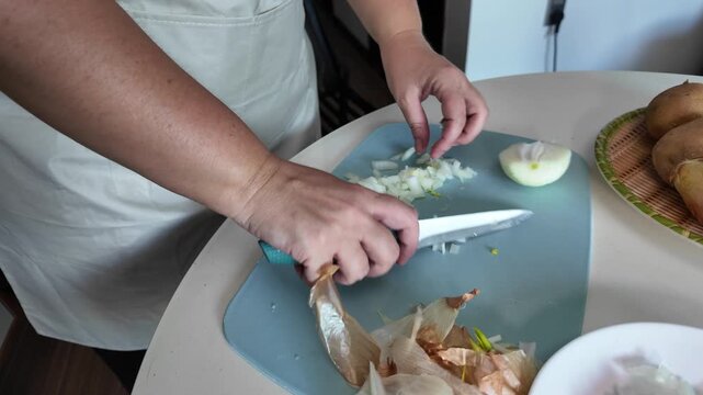Woman cuts peeled onions into small cubes