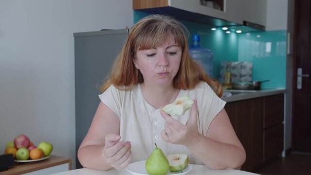 Woman eats a pear in the background of the kitchen