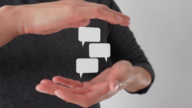 Close-up of a woman's hands shielding each other. An animation of several speech bubbles, in a chat format.