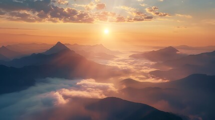Obraz premium Golden sun rays stream over layered mountain peaks covered in morning fog.