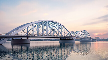 Modern steel arched bridge over calm river at sunset.