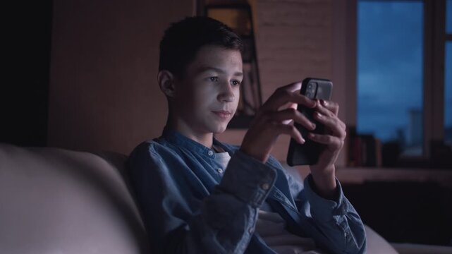 Quiet Evening: Boy Alone by the Window, Engrossed in His Phone