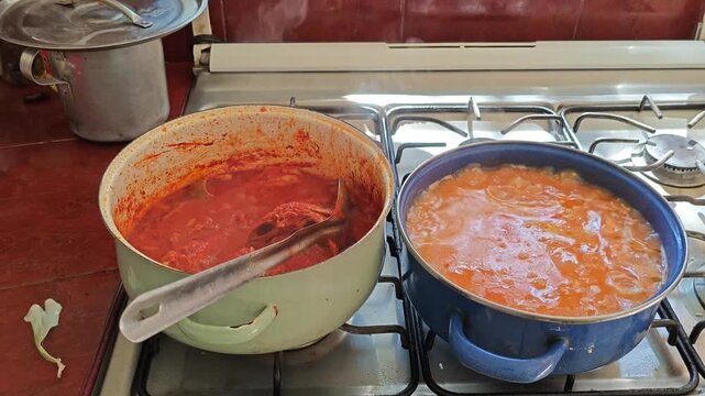 Moving a large pot of traditional red mole on a gas stove