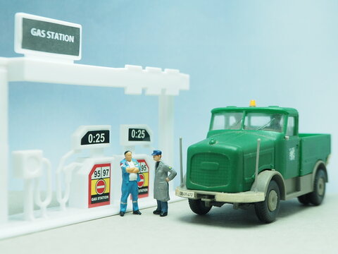 Mini toy of action figure at table with blurred background. Toy photography concept design. Heavy truck at gas station. Filling fuel at public gas station.