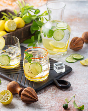 Summer lemon cucumber detox water with mint in glass tumblers and single solid teakwood handmade citrus reamers